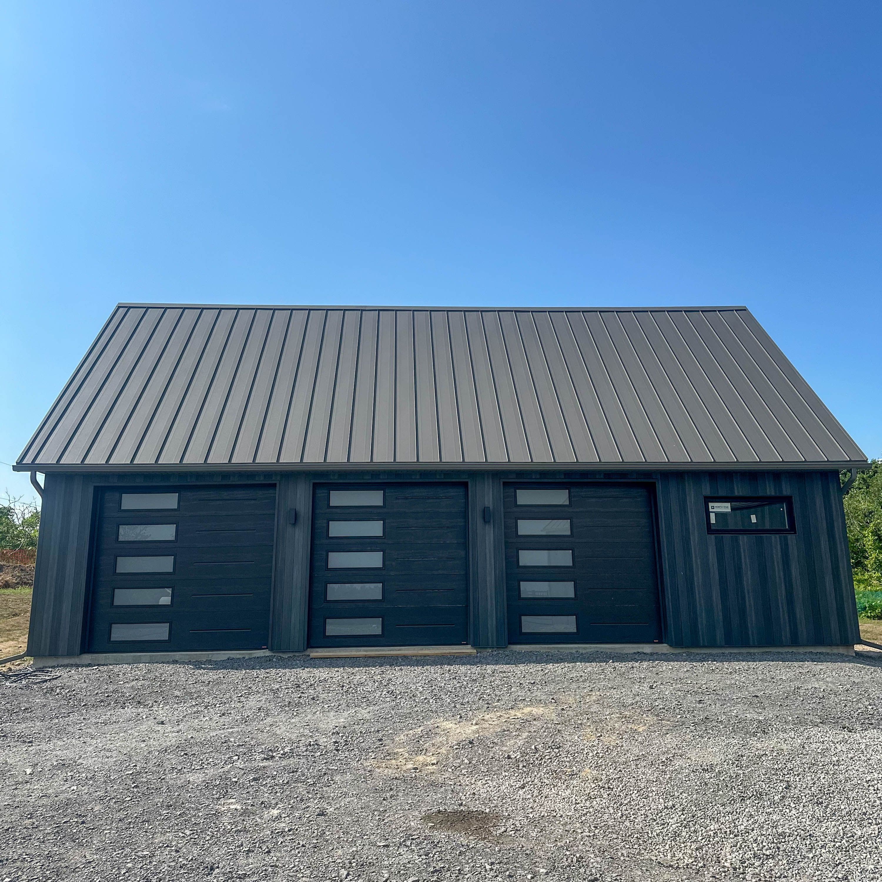 Modern steel exterior featuring dark wood grain siding and a high-performance metal roof system