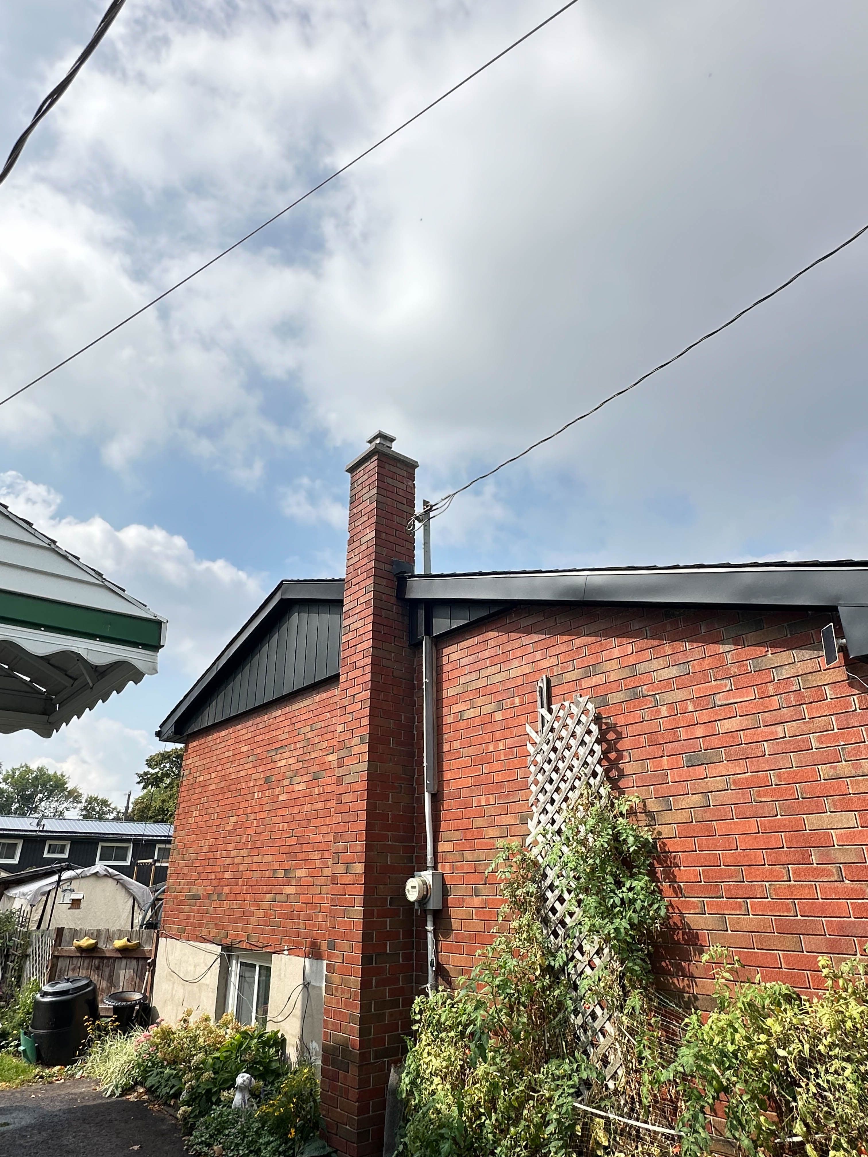 Gable end of a brick home featuring new black vertical siding and matching fascia installed in Belleville