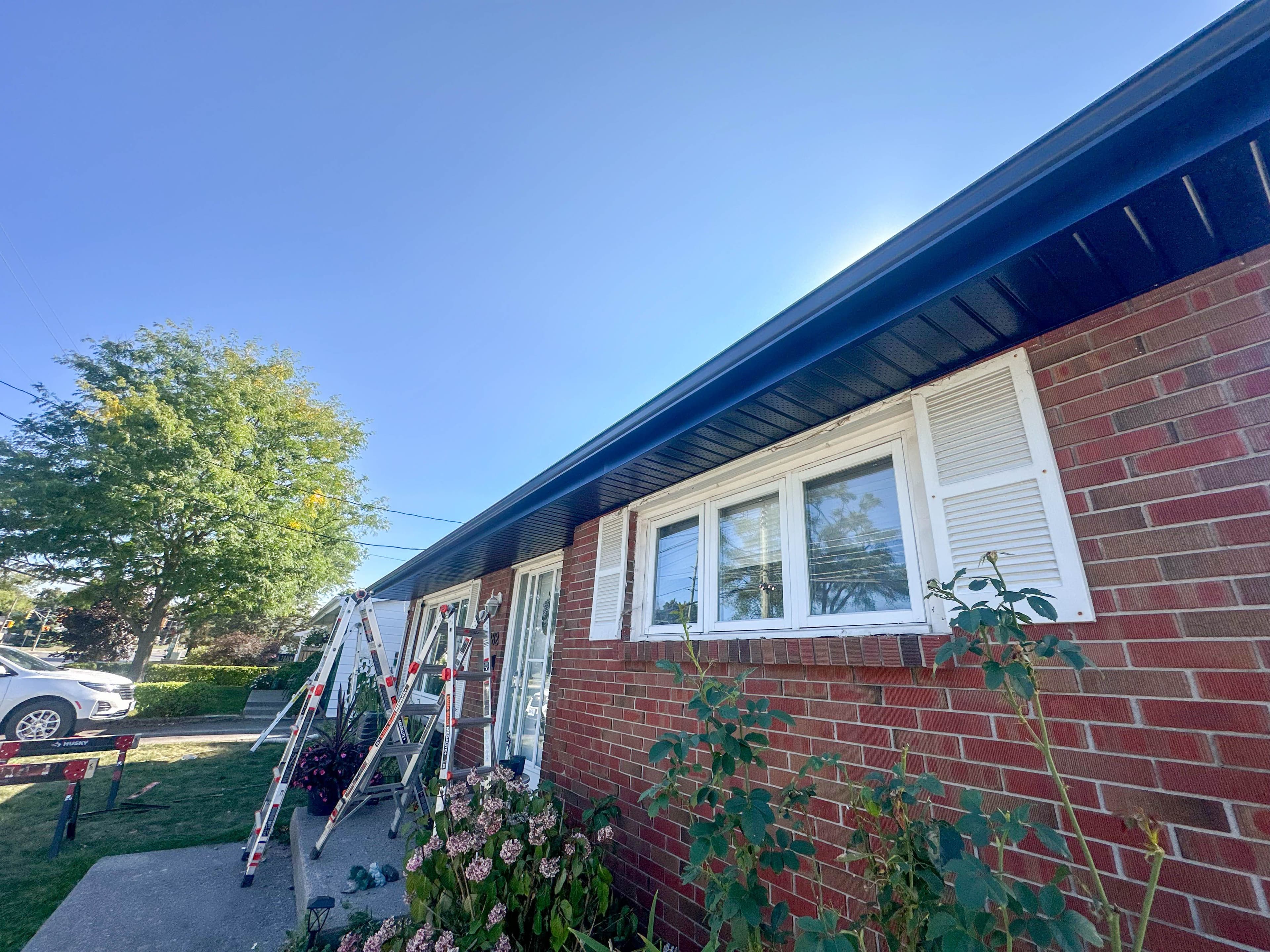 Front elevation of Belleville home mid-renovation with ladders set up for soffit and fascia installation