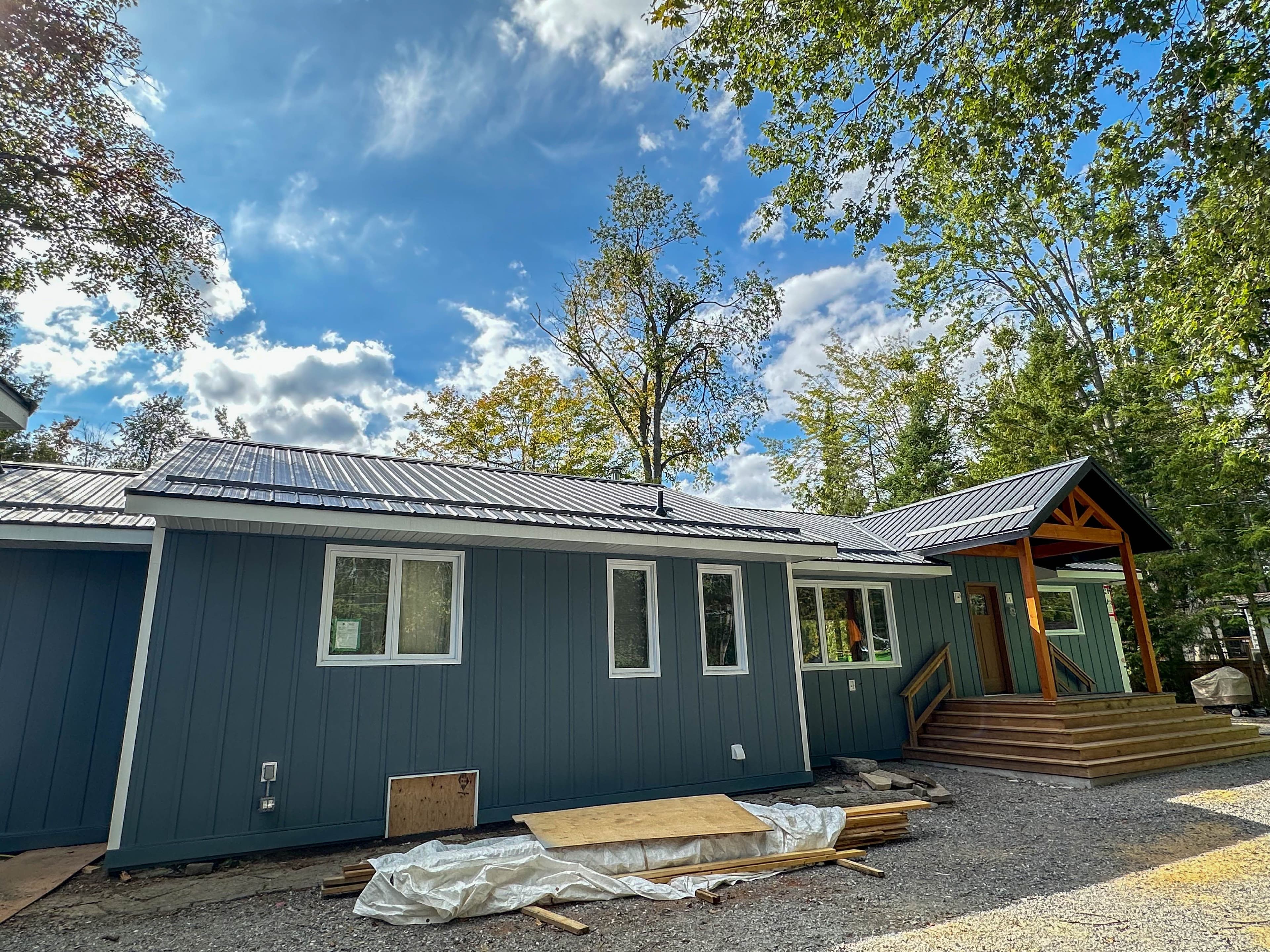 Completed Fenelon Falls home with Gentek Align composite siding, black steel roof, and natural wood porch posts