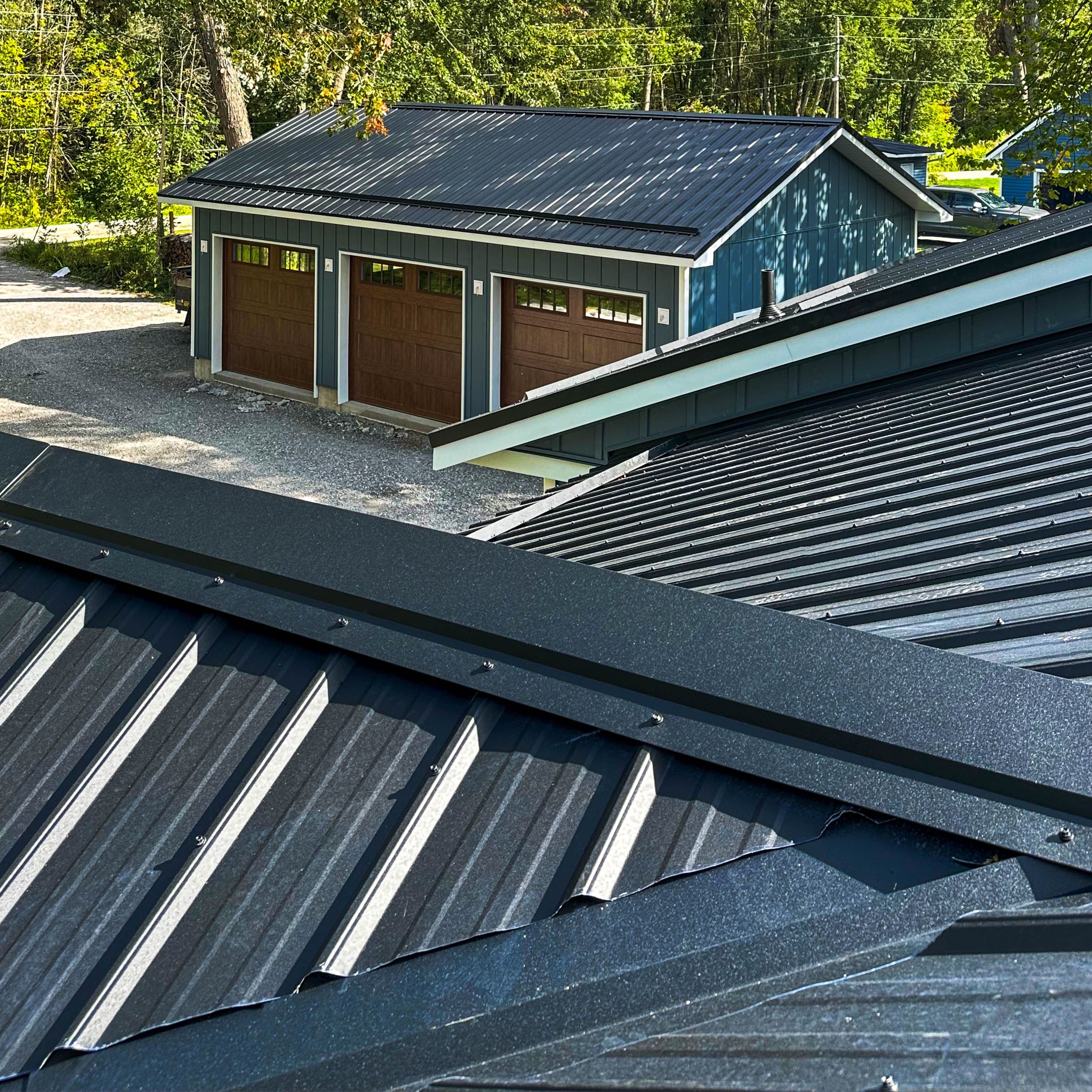 Close-up of black textured steel roofing on home and garage with exposed fasteners