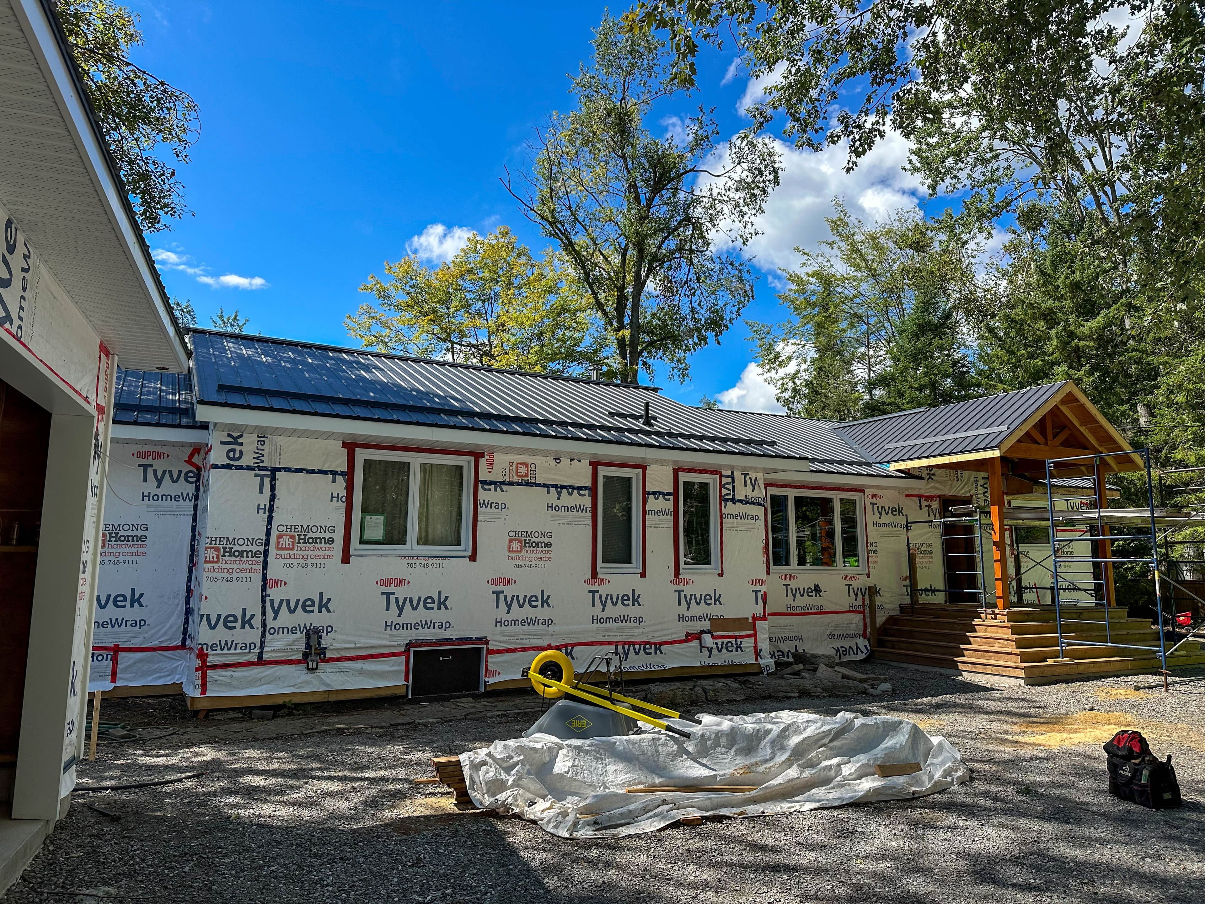 Exterior of Fenelon Falls home under construction with Tyvek wrap and steel roof installation in progress