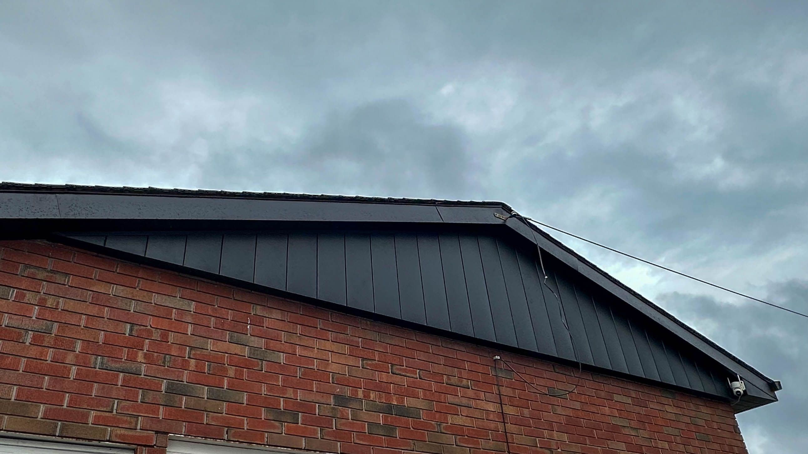 Black siding on gable ends of a brick home with matching fascia and soffit installation in Belleville