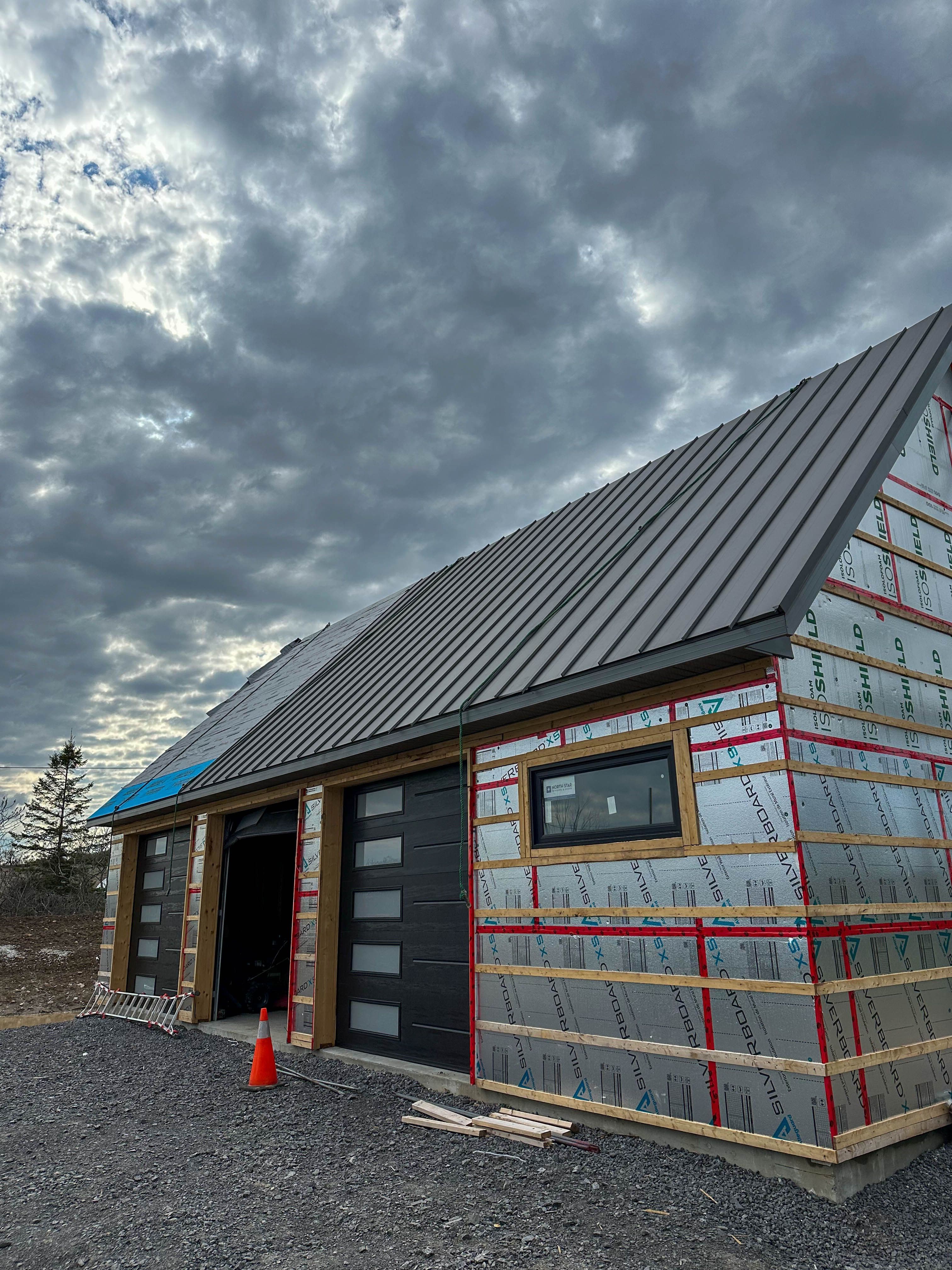 Close-up of modern exterior design showcasing metal roofing and Gentek Moderno siding in a sleek charcoal finish
